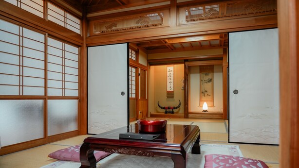 A traditional Japanese room with tatami flooring, a low wooden table, and sliding doors. - In a quiet, green environment, with free parking, your room is in the middle of the ocean, you have your own spacious wooden room, a spacious living room with outdoor seating, and your own private garden with a roast fireplace. (由布市湯布院町川上)