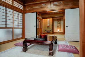 A traditional Japanese room with tatami flooring, a low wooden table, and sliding doors. - In a quiet, green environment, with free parking, your room is in the middle of the ocean, you have your own spacious wooden room, a spacious living room with outdoor seating, and your own private garden with a roast fireplace. (由布市湯布院町川上)