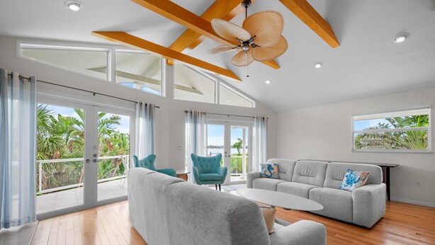 Un salon spacieux avec un haut plafond, de grandes fenêtres et un ventilateur de plafond.