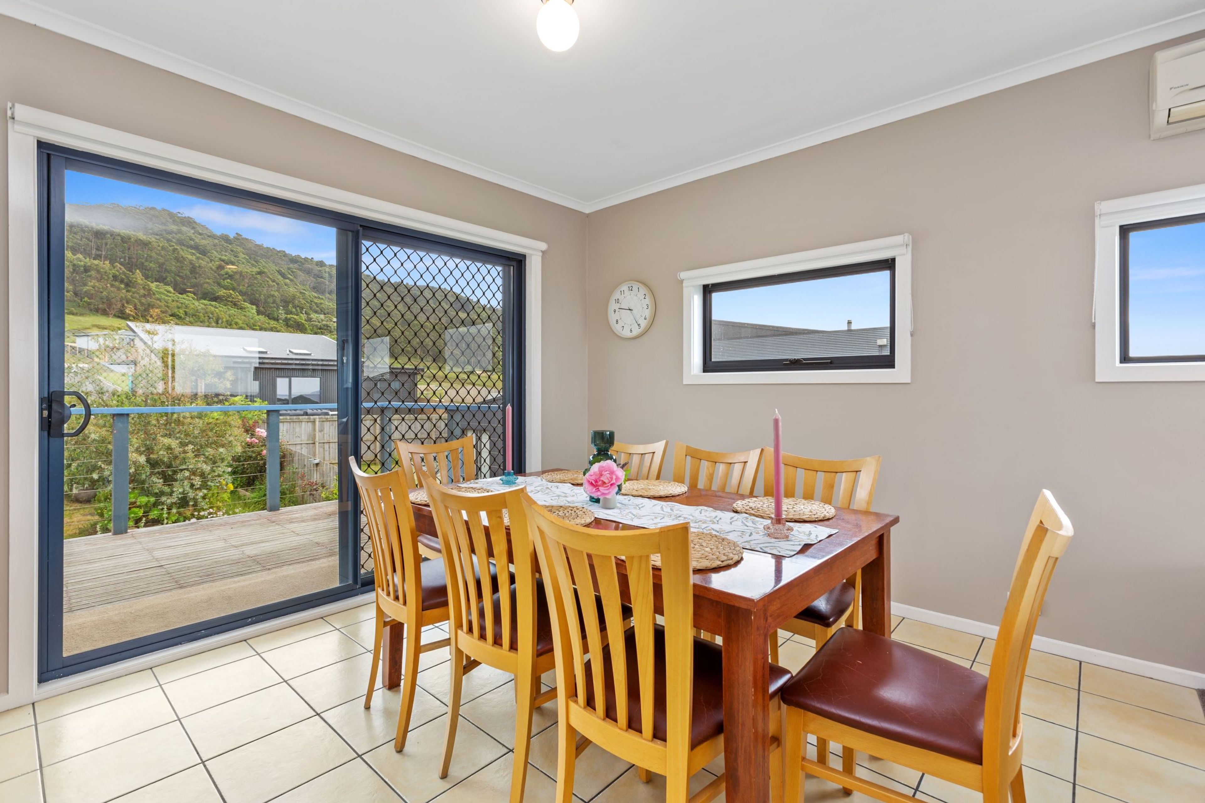 A dining area with a table set for four, surrounded by wooden chairs with leather seats.