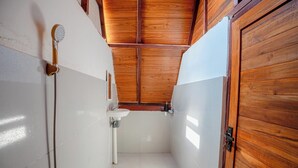 Un baño estrecho con techo de madera, un lavabo blanco y una ducha.