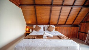 Un dormitorio con estructura de madera, cama grande, ropa de cama blanca y cabecera de madera.