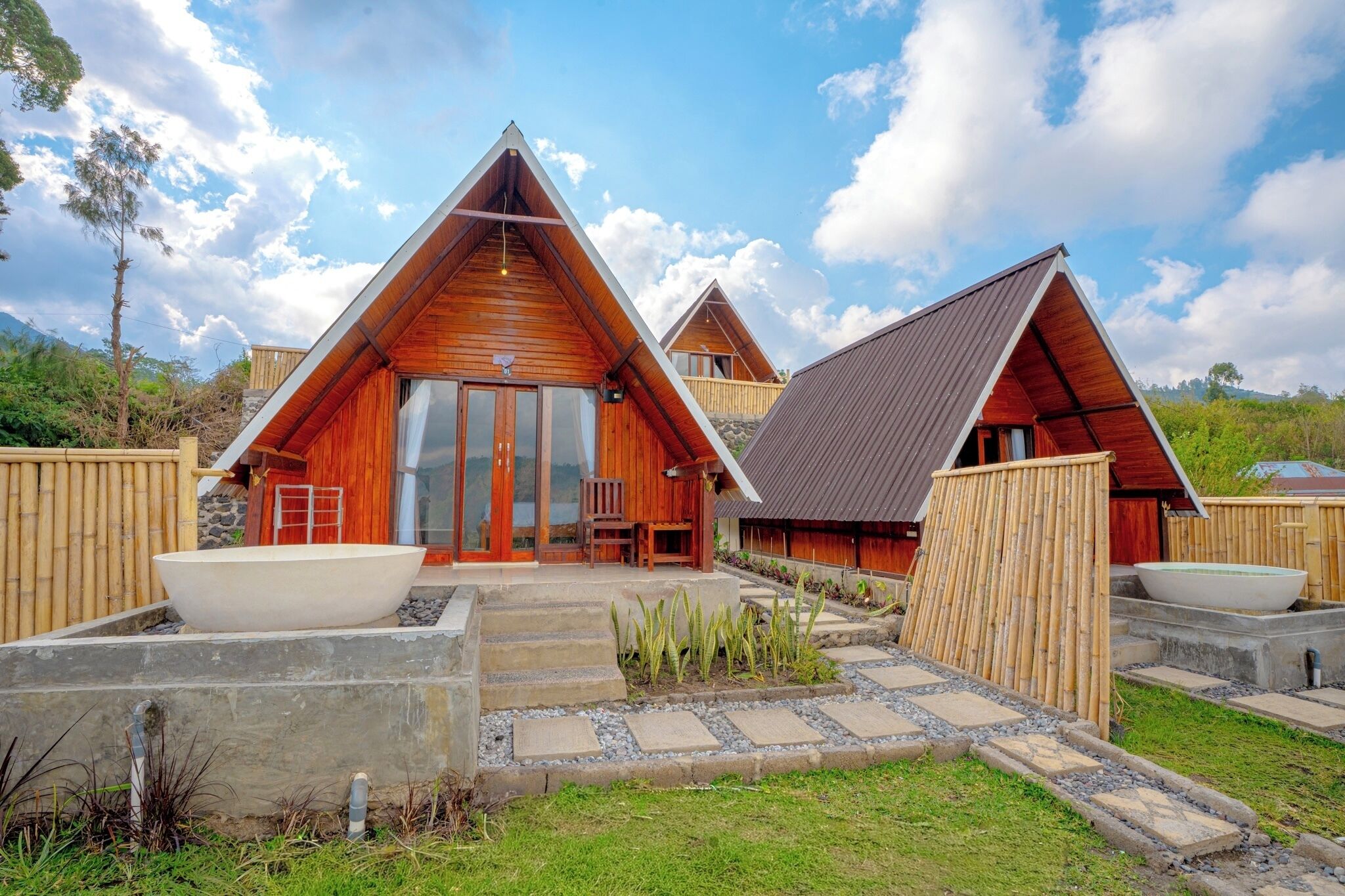 A modern bungalow with a triangular roof, large windows, and a stone pathway leading to the entrance.