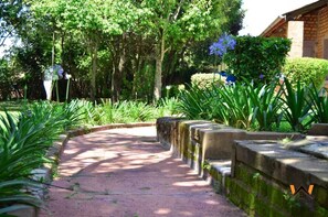 A garden pathway with stone steps, surrounded by lush greenery and trees. - Waikiki Guest House Kiminini (Kiminini)