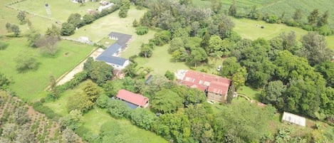 An aerial view of a rural property with multiple buildings, green fields, and scattered trees.