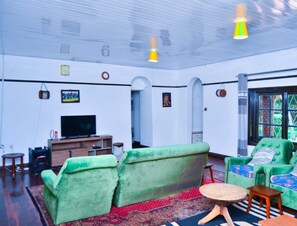 Un salón amplio con sofás verdes, un televisor y un tapete rojo con estampado.