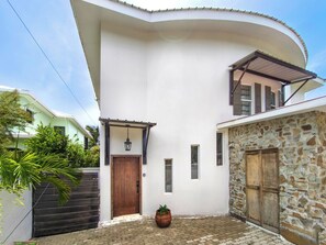 A two-story building with a white exterior, a wooden door, and a stone wall.