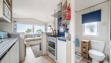 A compact kitchen with a stove, oven, and a small dining area with a sofa.