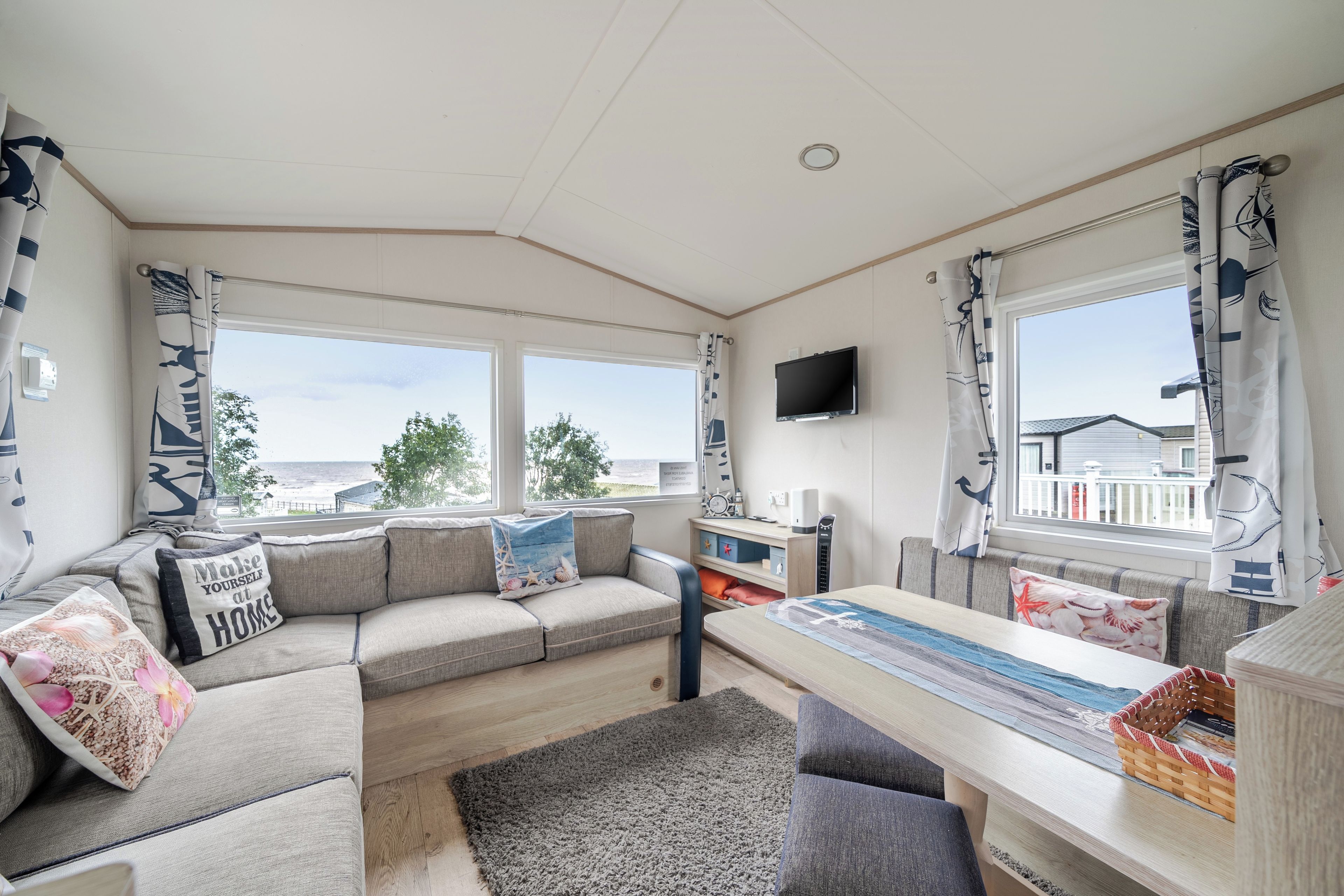 A modern living room with a sofa, a dining table, and a TV mounted on the wall.