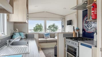 A compact kitchen with a stove, sink, and a window overlooking greenery.