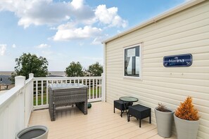A covered outdoor area with a wicker table and chairs, a potted plant, and a sign indicating the property is for rent. - Cabin - Sleeps 4 - Pets Ok - Balcony - Parking (Watchet)