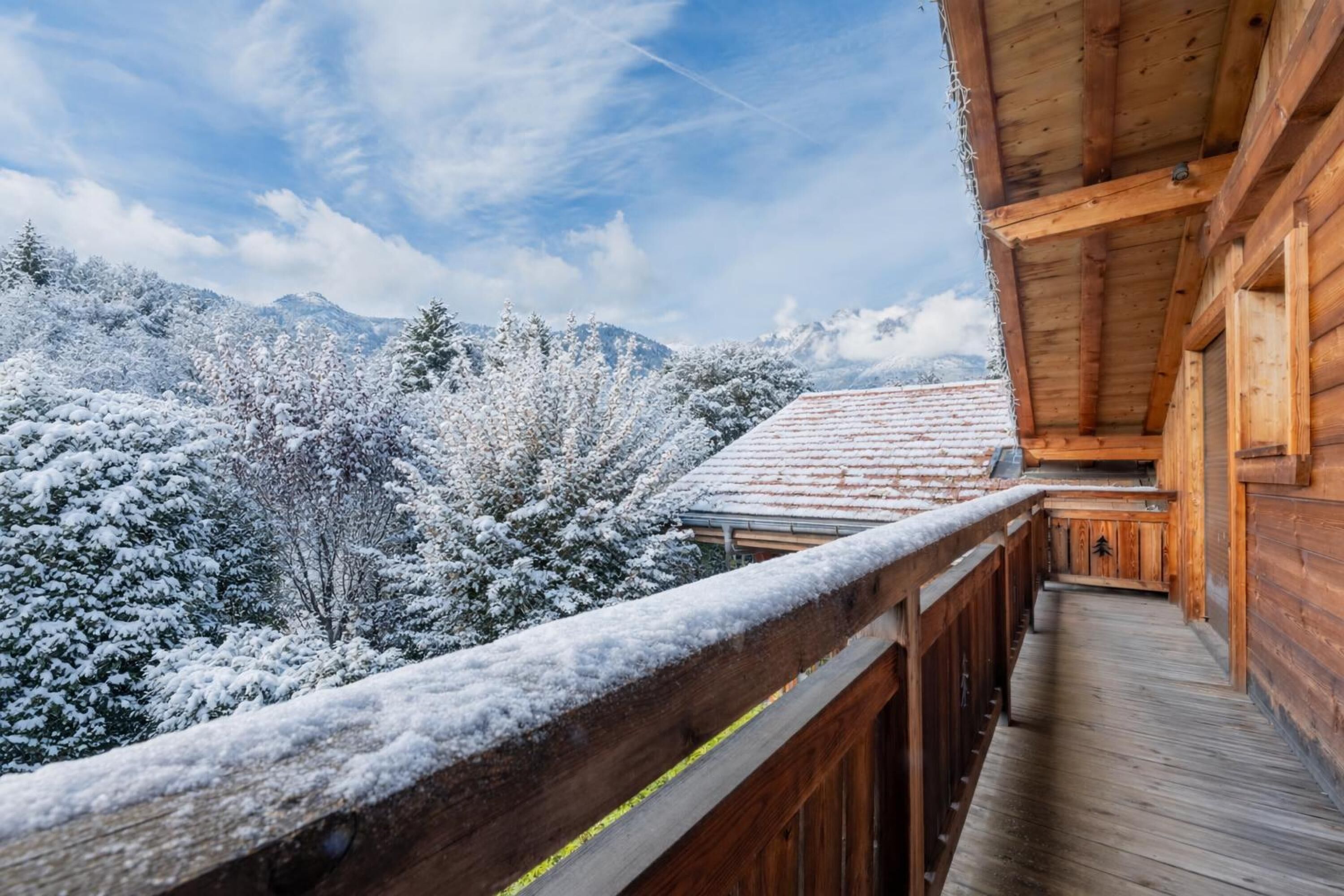 Een houten chalet met balkon, met uitzicht op een besneeuwd berglandschap.