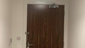 A room with a wooden door, a ceiling light fixture, and a wall-mounted thermostat. - 1 Bed Flat- Direct Links to Central London (Grays)