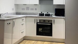 A modern kitchen with white cabinets, a stainless steel oven, and a black microwave. - 1 Bed Flat- Direct Links to Central London (Grays)