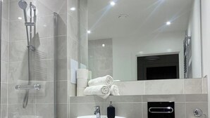 A modern bathroom with a glass-enclosed shower, a sink, a toilet, and a mirror. - 1 Bed Flat- Direct Links to Central London (Grays)