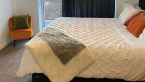 Een slaapkamer met een bed, een stoel en uitzicht op de omgeving.