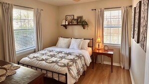 Una camera da letto con un letto, un comodino, una lampada e tende.