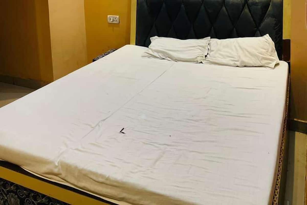 A hotel room with a large bed, a tufted headboard, and a ceiling with purple LED lighting.