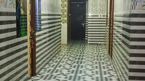 Un pasillo con baldosas de suelo estampadas, paredes pintadas de verde y rosa, y una puerta al final.