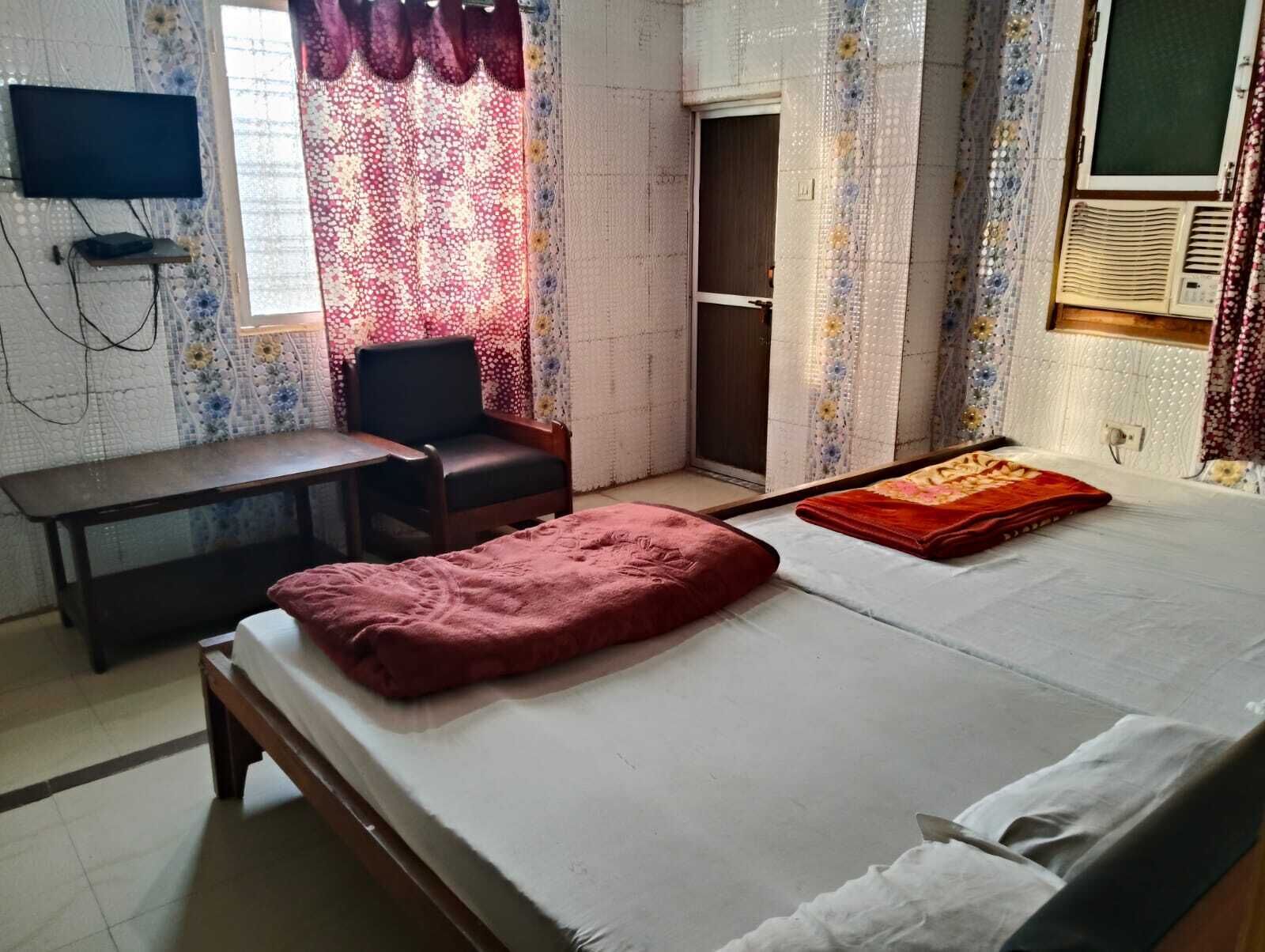 A room with a bed, a desk, a chair, and a television.