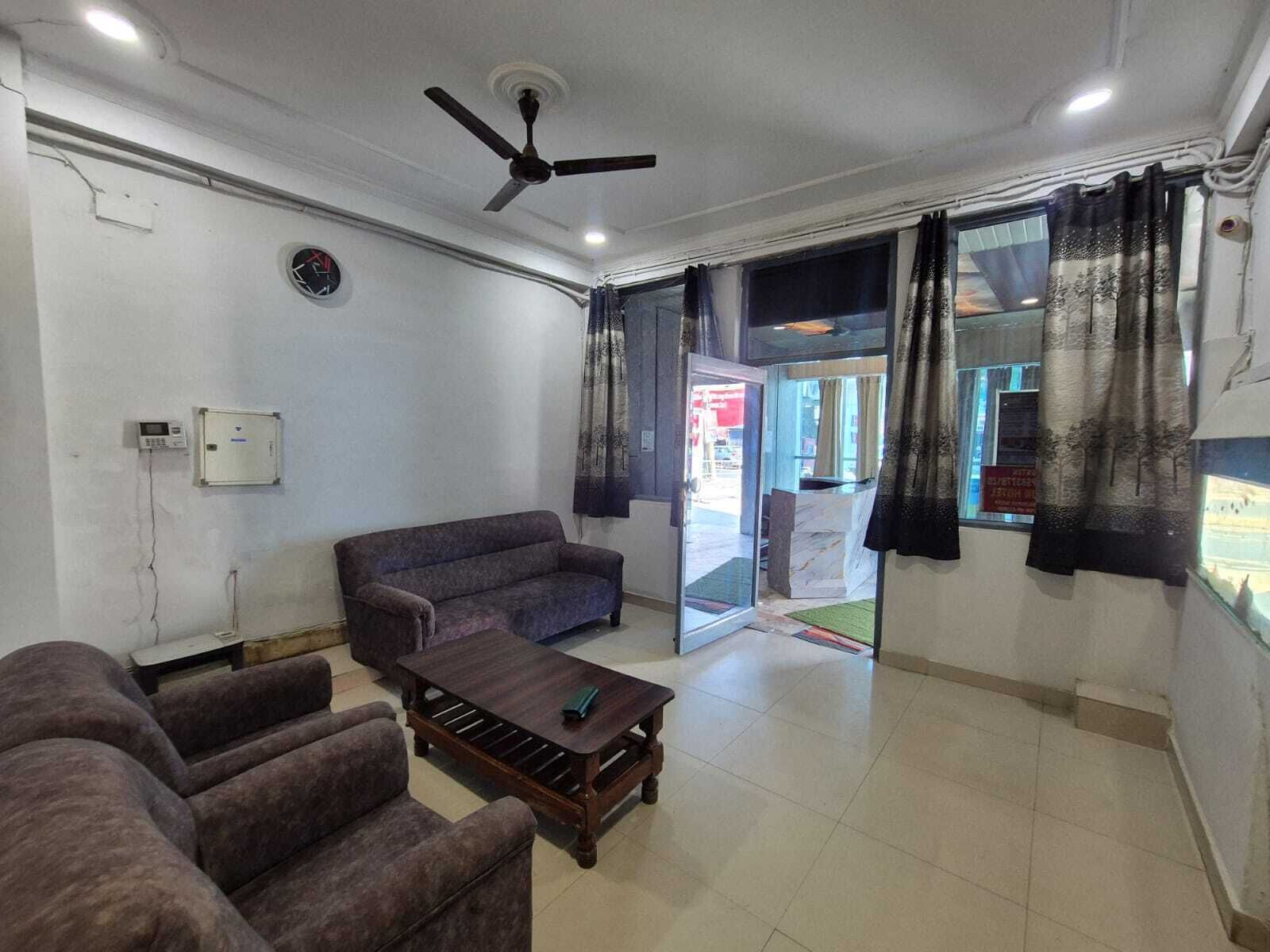 Una sala de estar con sofá, sillones, una mesita de centro, ventilador de techo y vistas al exterior a través de un ventanal.