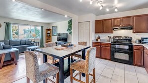 Une cuisine moderne avec des meubles en bois foncé, une cuisinière noire et un four à micro-ondes. On y trouve également un coin repas avec une table et des chaises à motifs.