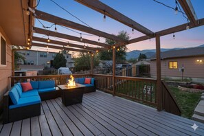 A wooden deck with a built-in fire pit and blue outdoor furniture. - Fire Pit ~ Games ~ Pets ~ Views ~ 2 mins to OCC (Colorado Springs)