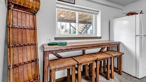 Une cuisine avec un banc en bois, un réfrigérateur blanc et une fenêtre donnant sur un immeuble.