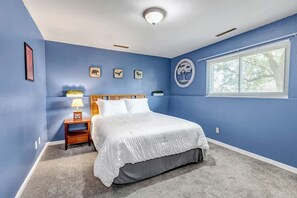 A bedroom with a bed, a nightstand, a lamp, and a window with blinds.