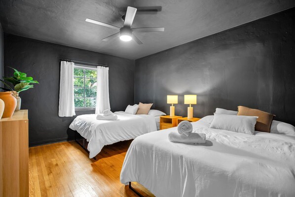 A hotel room with two beds, a ceiling fan, a window with white curtains, and a potted plant. - Villa in the heart of design district! POOL+LOCATION (Miami)