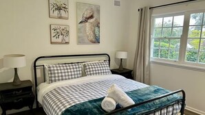 Een slaapkamer met een bed, twee nachtkastjes en een raam met gordijnen.