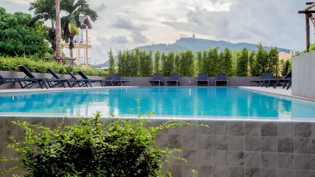 Une piscine entourée de chaises longues, de verdure et offrant une vue sur des collines lointaines.