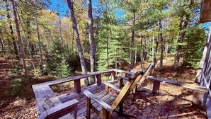 A wooden deck with benches, surrounded by trees. - Tig Foster on Madeline Island (LaPointe)