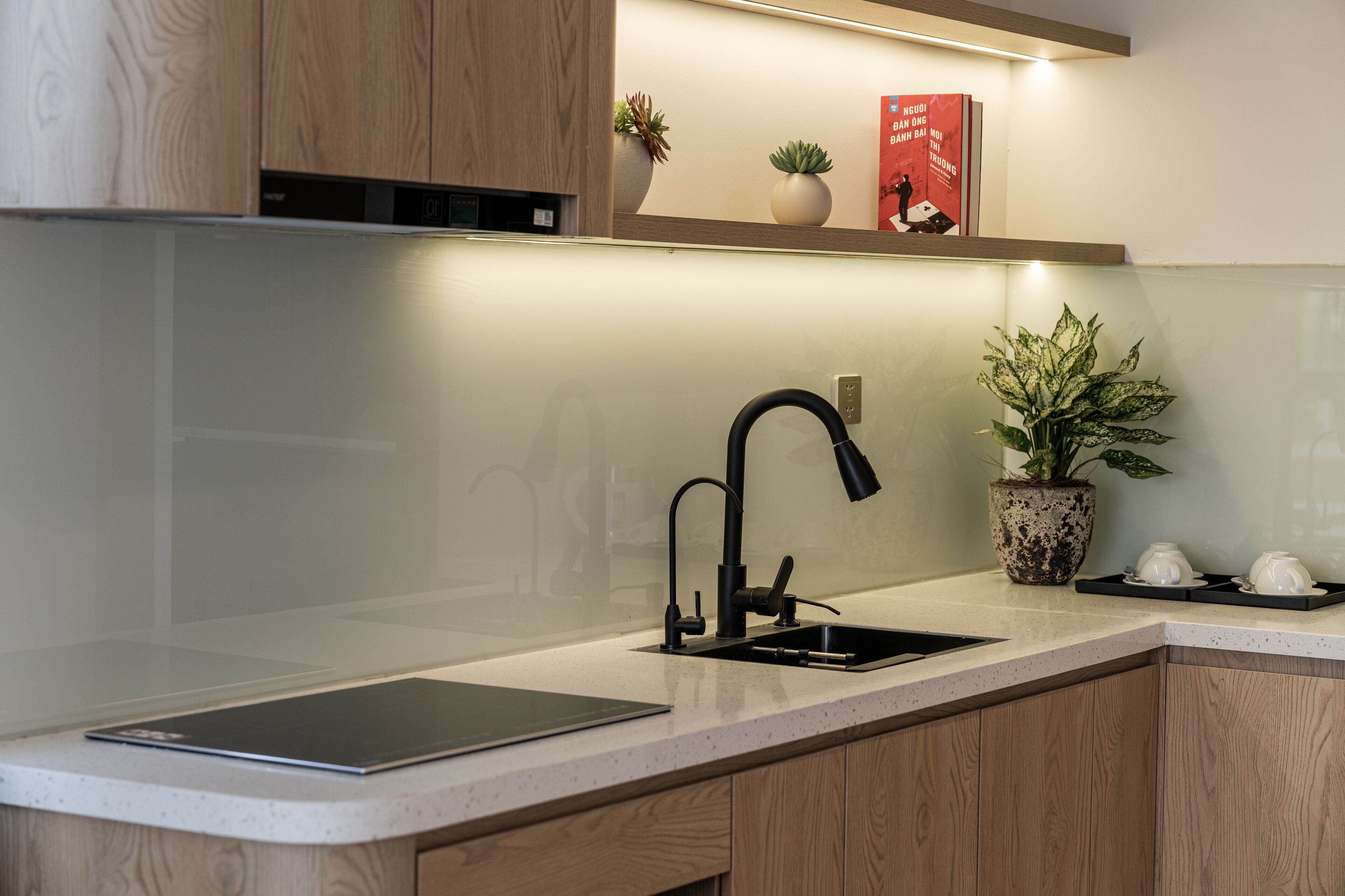 A modern kitchen with a black faucet, a built-in oven, and a countertop with a tablet.