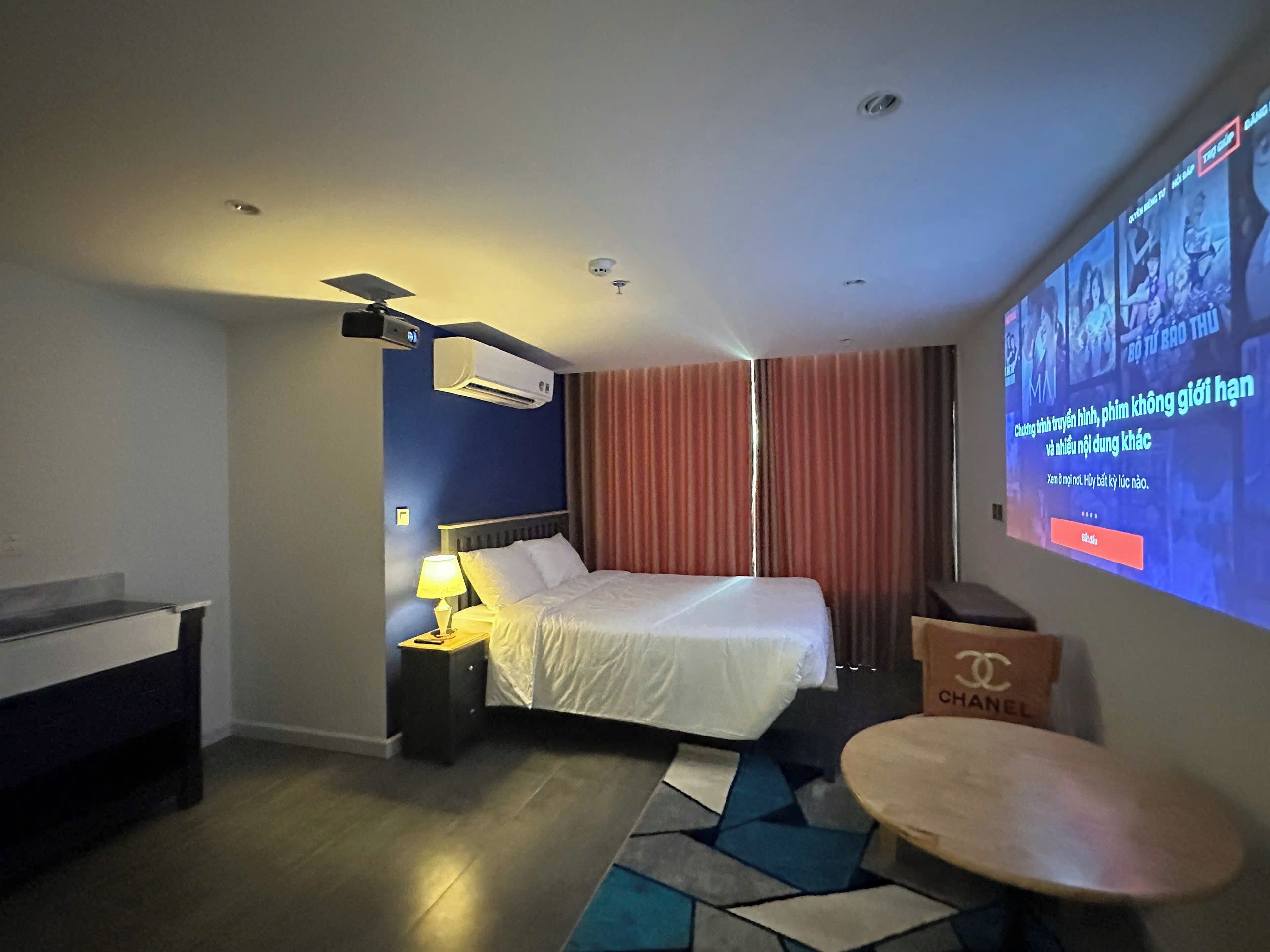 Une chambre d’hôtel équipée d’un lit, d’un bureau, d’une chaise, d’un écran de télévision et d’un climatiseur fixé au mur.