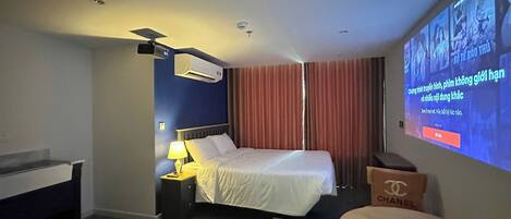 Une chambre d’hôtel équipée d’un lit, d’un bureau, d’une chaise, d’un écran de télévision et d’un climatiseur fixé au mur.