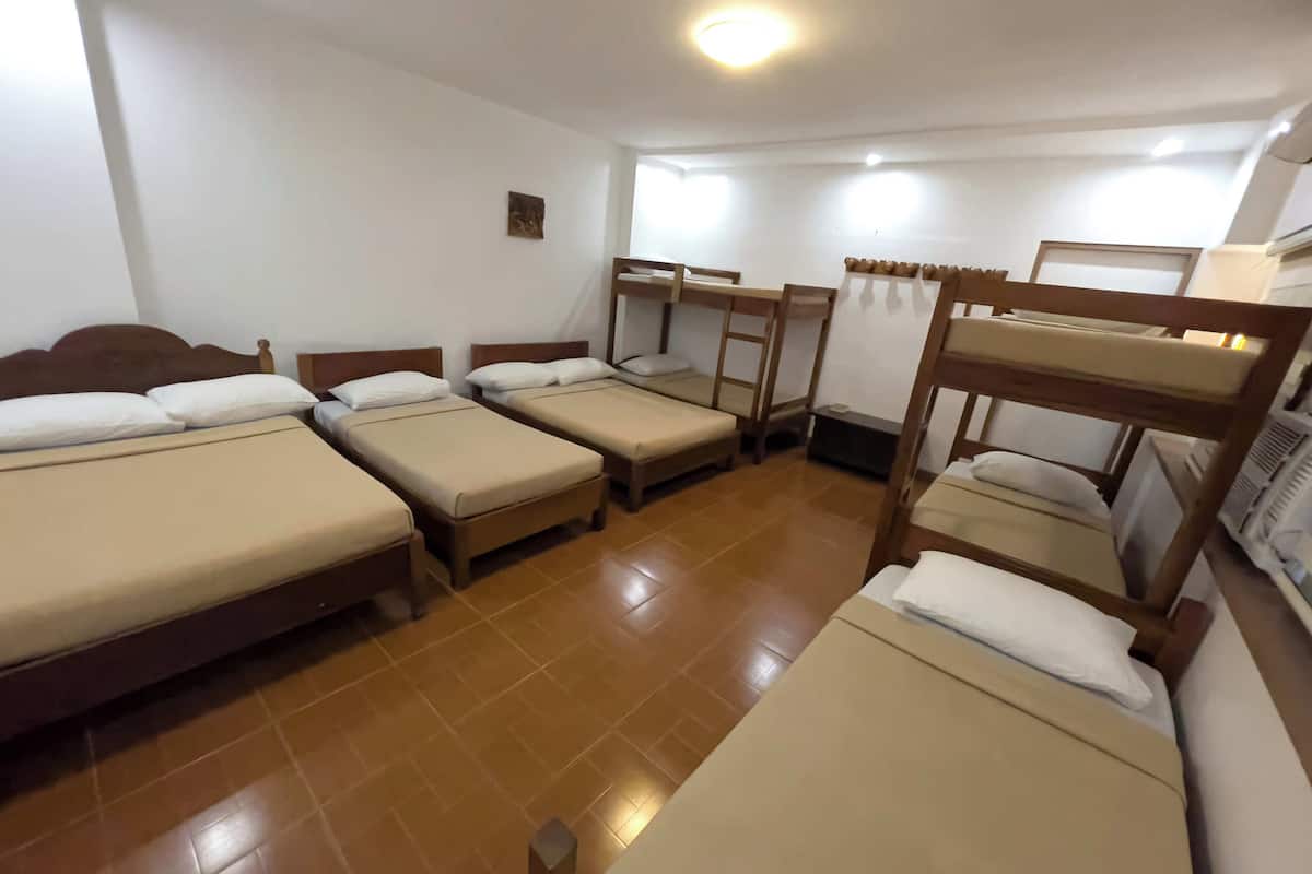 Un dormitorio con cuatro literas, piso de baldosas y una ventana pequeña.