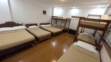 A dormitory room with four bunk beds, a tiled floor, and a small window.