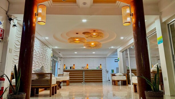 A hotel lobby with a modern design, featuring a central reception desk, seating area with sofas and chairs, and decorative lighting fixtures. - Sebay Surf Central San Juan La Union (San Juan)