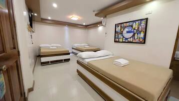 Habitación de hotel con dos camas individuales, una cama grande, un cuadro en la pared y una puerta con un letrero.