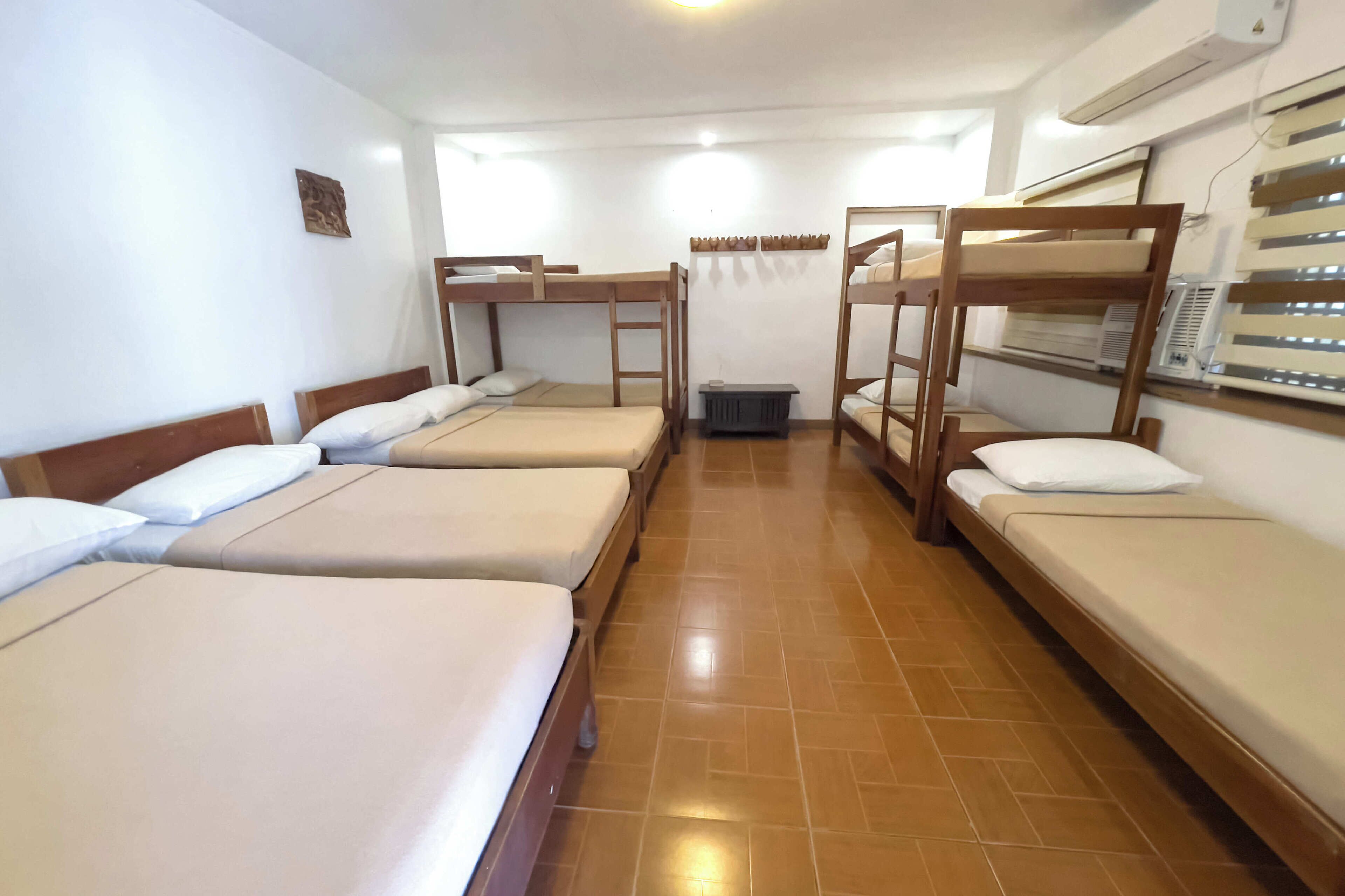 Un dormitorio con literas, un cubo de basura pequeño y un equipo de aire acondicionado.