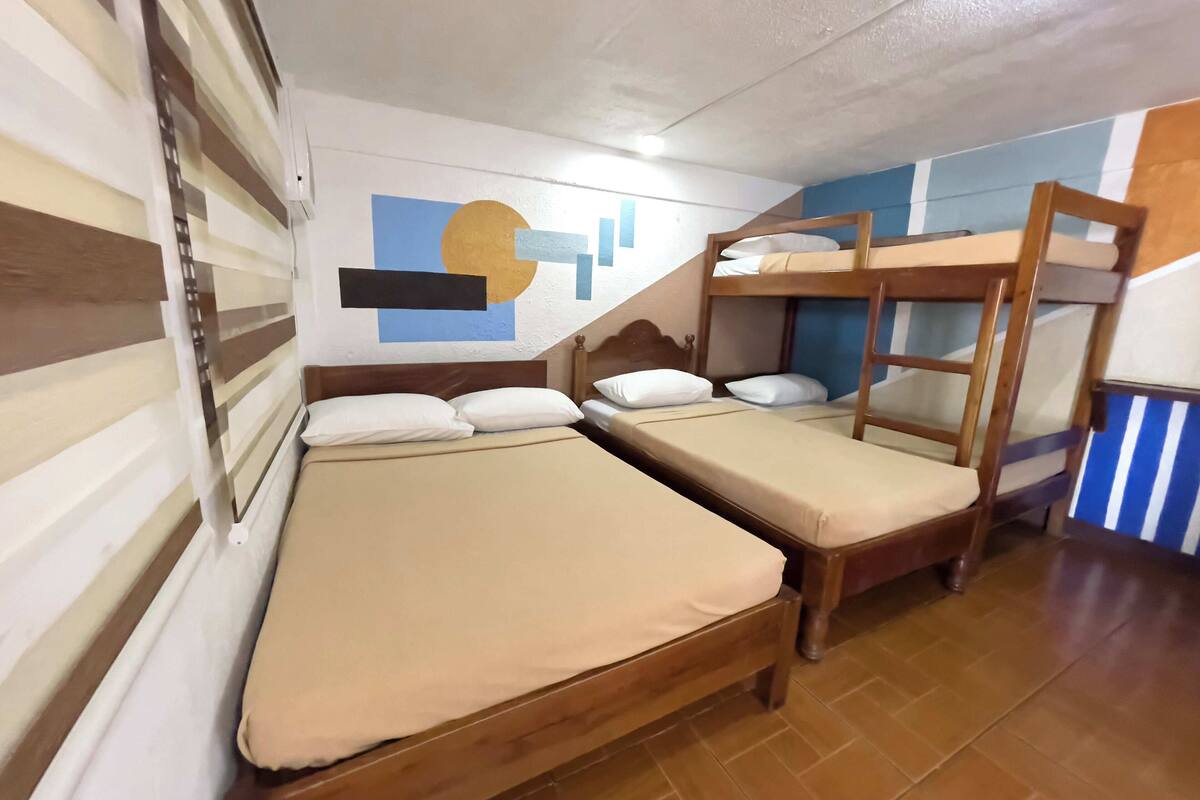 Una habitación con literas, un cabecero de madera y una pared con un diseño geométrico.