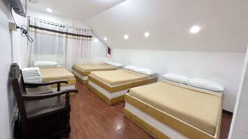 Una habitación de hotel con tres camas individuales, un banco de madera y un escritorio.
