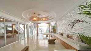 A modern hotel lobby with a central seating area, a staircase, and a view of the outside. - Sebay Surf Central San Juan La Union (San Juan)