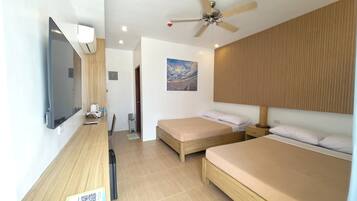 A hotel room with two beds, a ceiling fan, a TV, and a painting on the wall.