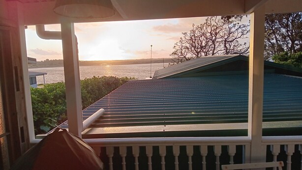 Un porche techado con vistas a la puesta de sol sobre el agua.