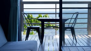 A balcony with a table and chairs, overlooking a body of water and distant mountains. - costadelsol-hiji (Hiji)