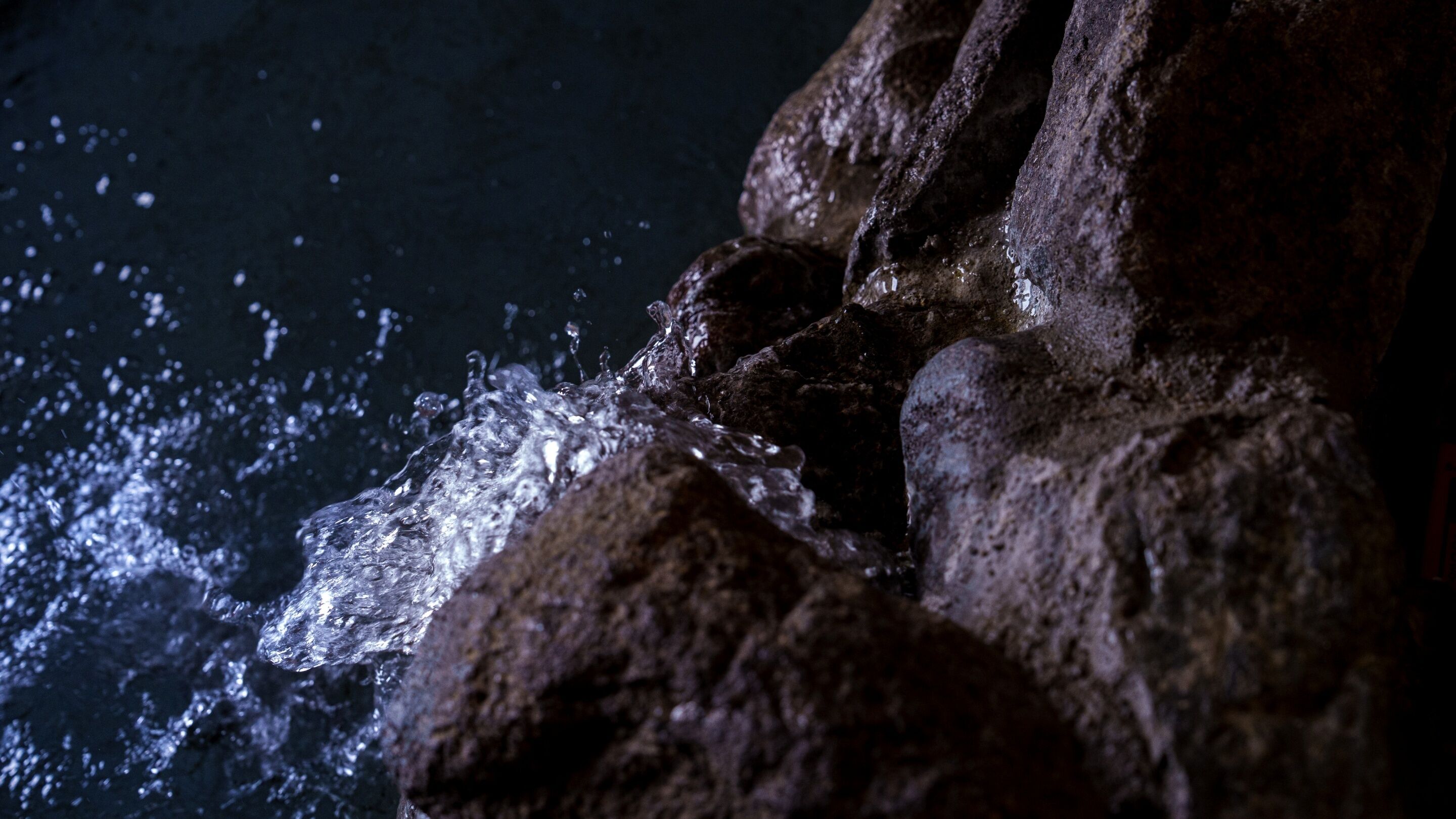 A close-up of a rocky surface with water splashing against it.