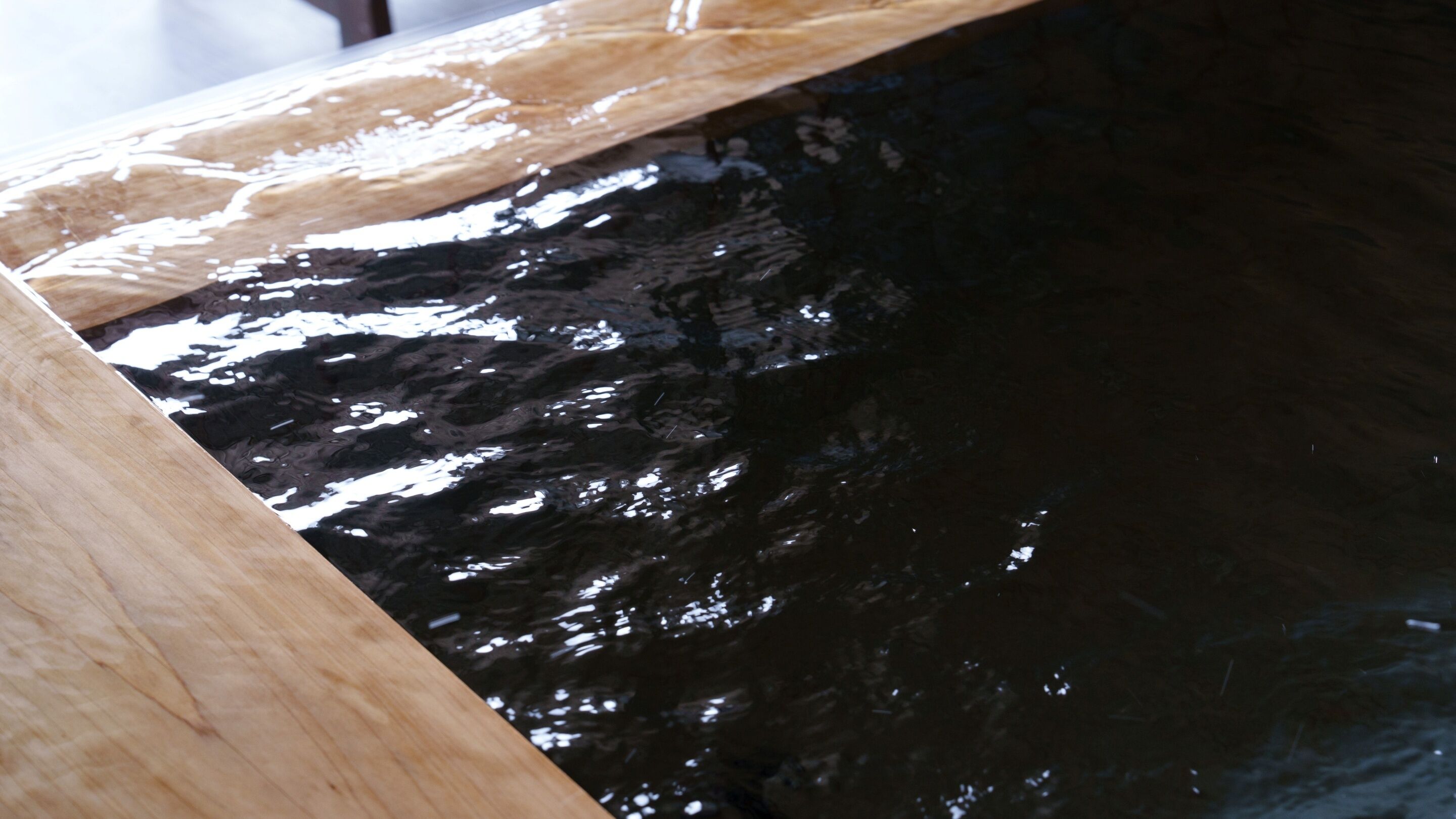 Primer plano de una superficie de madera con un material negro brillante debajo.
