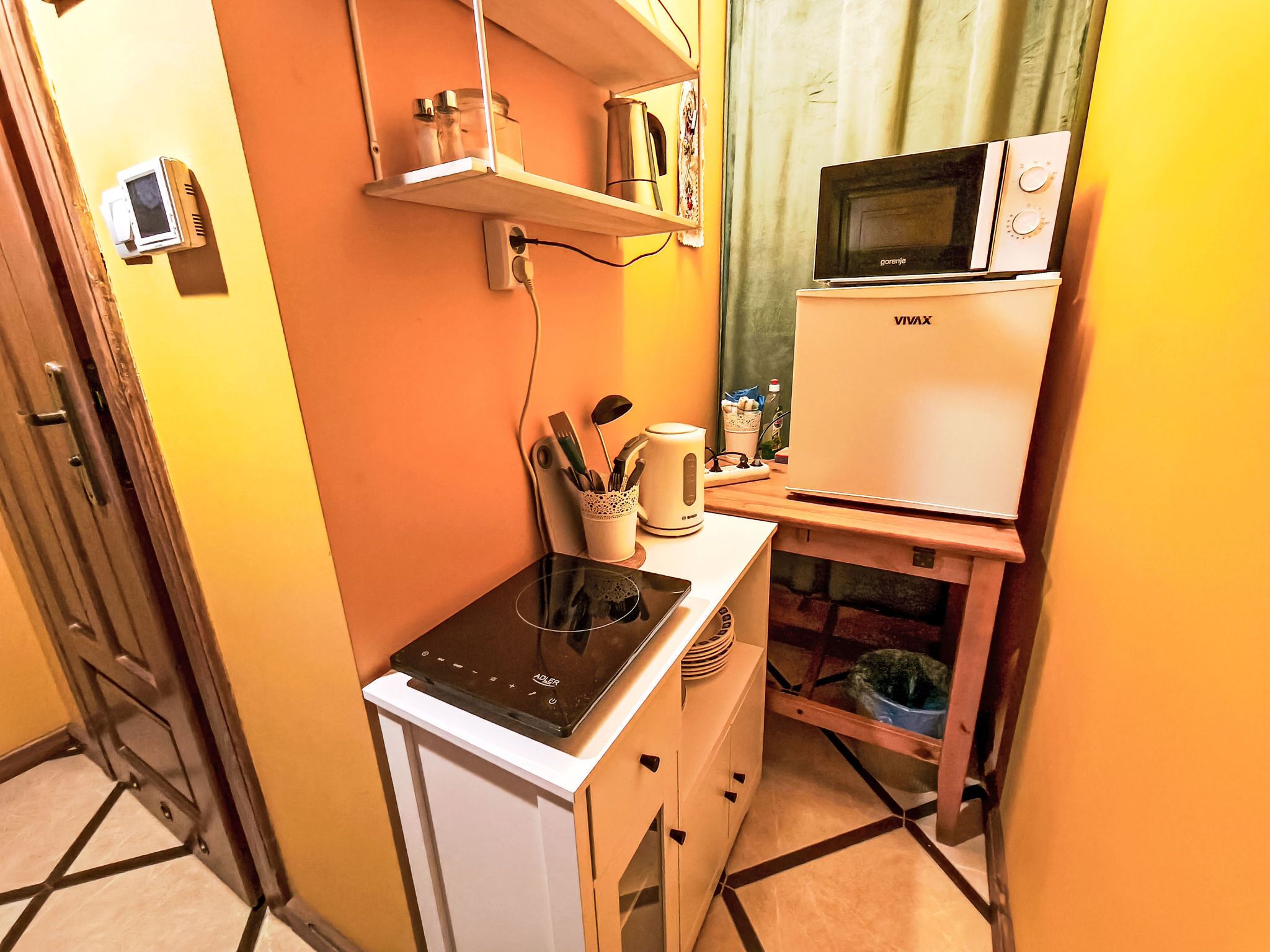 A compact kitchenette with a refrigerator, microwave, and electric kettle.